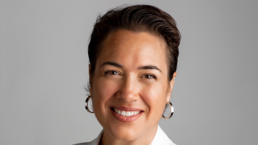 A woman wearing a white jacket smiling