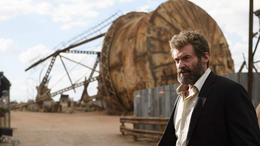 Actor Hugh Jackman stands in a suit in the film Logan.