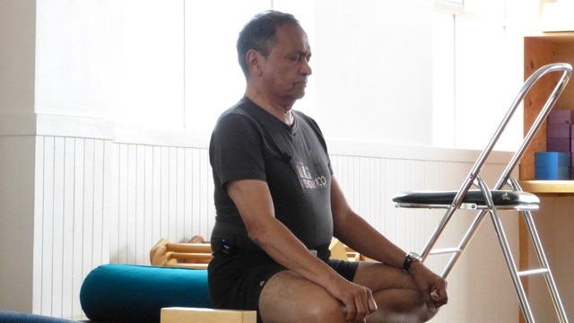 An Indian man seated on the floor cross legged with eyes shut