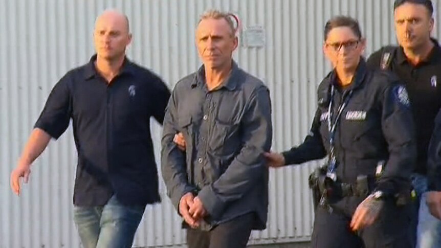 Police escort Bernd Neumann out of the Perth airport.