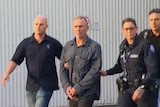 Police escort Bernd Neumann out of the Perth airport.