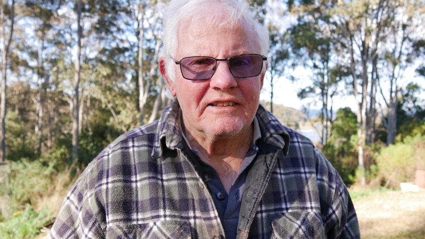 An elderly man in transition lenses and a flannel overshirt.