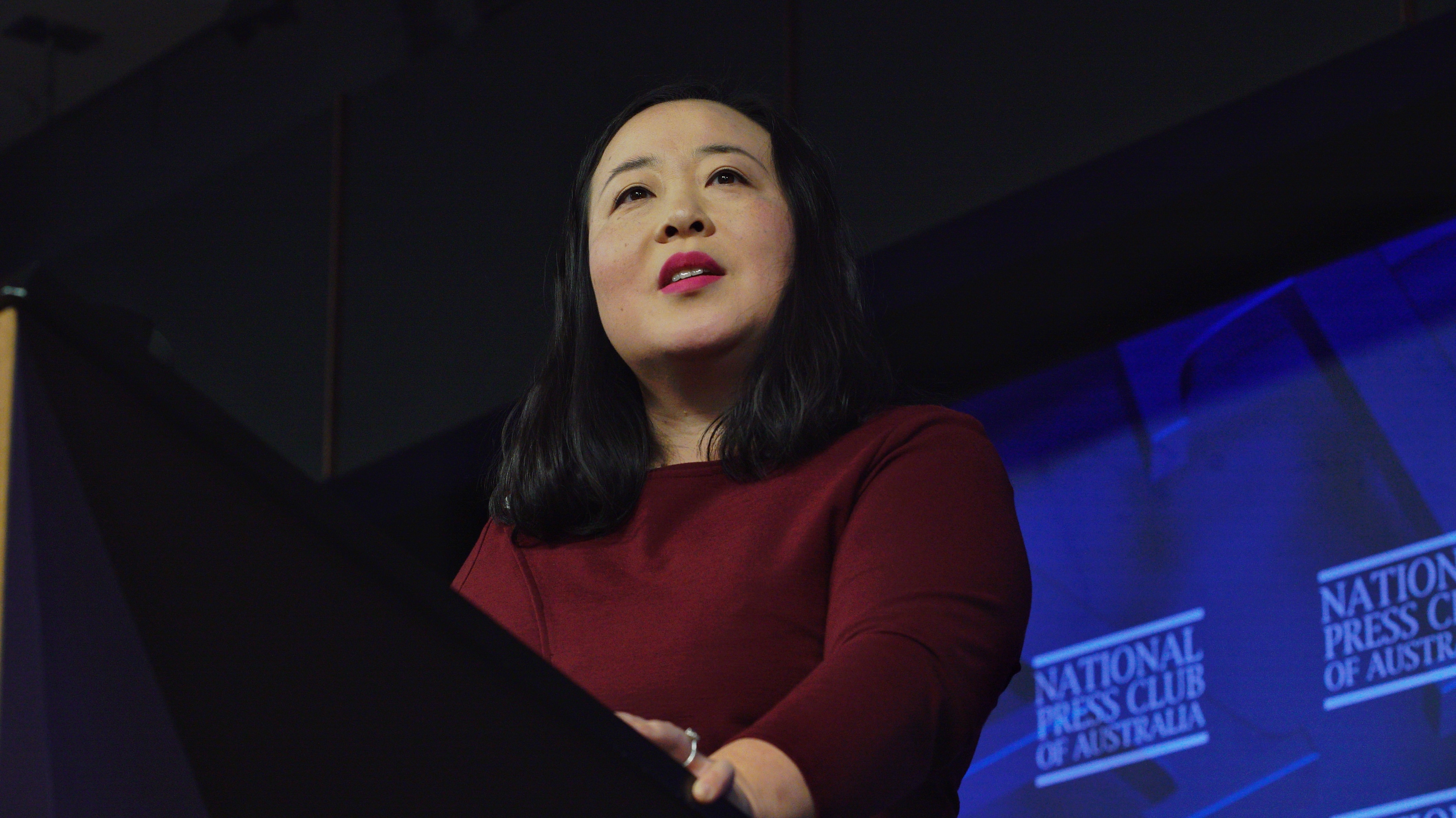 Elizabeth Lee stands behind a podium while giving a speech.