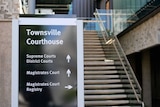 Out the front of Townsville court house with a sign giving directions on where each court room is located.