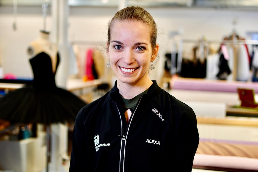 A head and shoulder shot of Alexa Tuzil who is smiling and pictured in front of set costumes