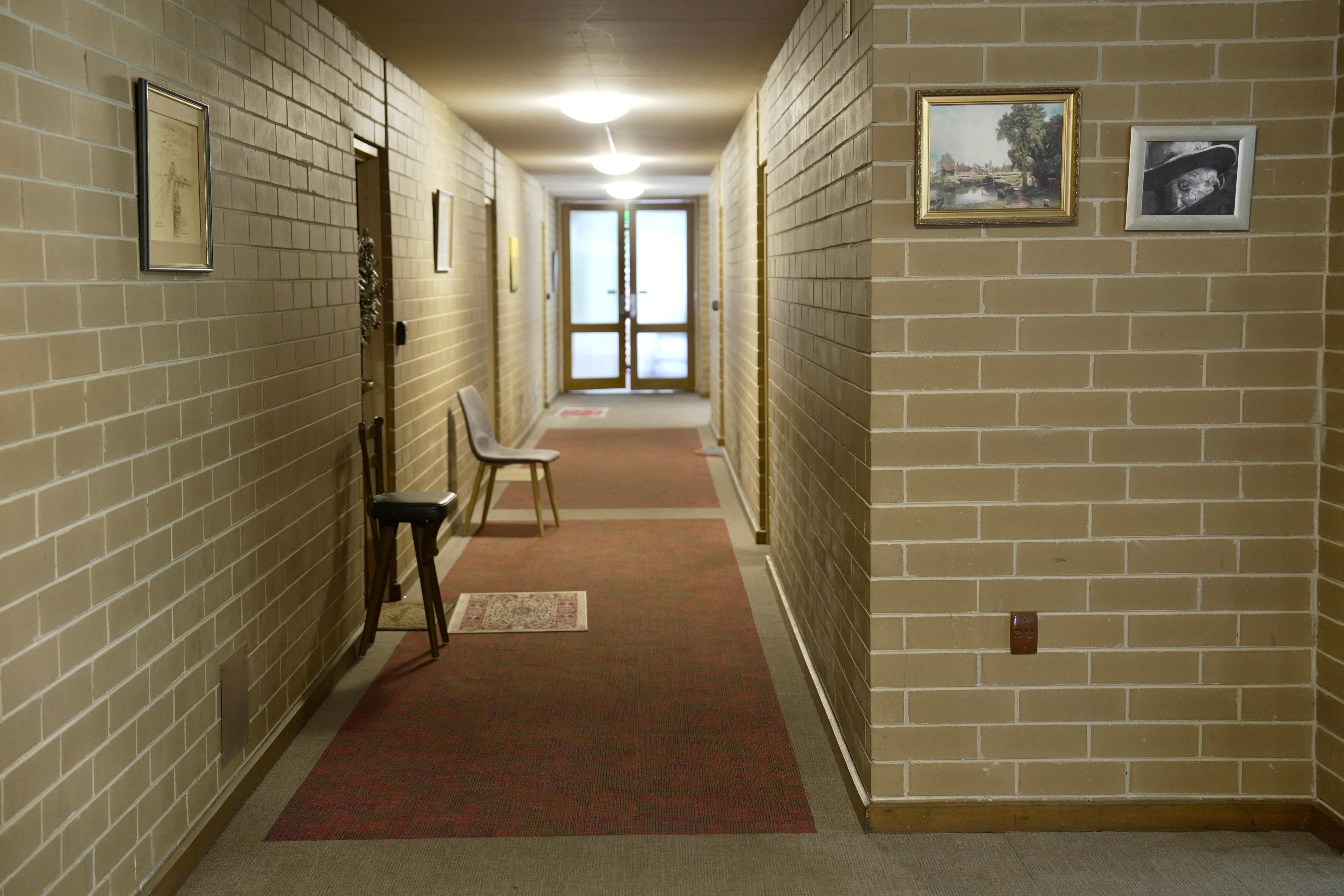 Un pasillo en Glenloch con ladrillos beige y alfombra marrón.