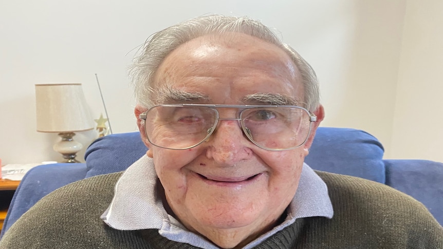 A close up of an elderley man wearing glasses and a big smile.