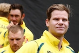 Steve Smith and the Australian cricket team stand on the boundary during a rain delay.