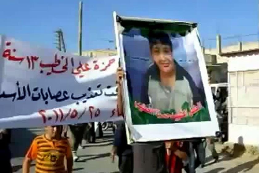 A Syrian man holds a photo of 13-year-old boy, Hamza al-Khatib, during his funeral on May 25, 2011.