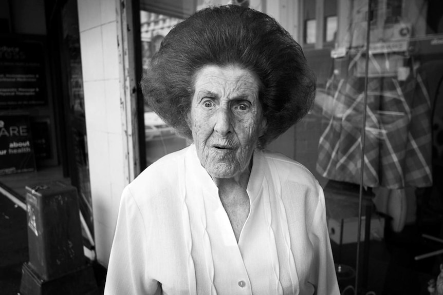 An elderly woman with a bouffant hairdo.