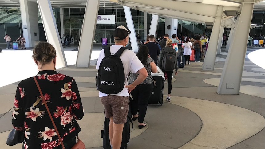 A line up of people with their luggage outside Adelaide Airport