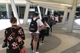 A line up of people with their luggage outside Adelaide Airport