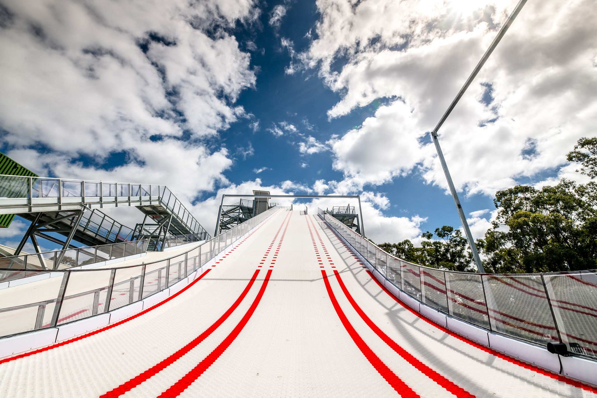 A low view looking up of a steep white and red track with clouds and blue sky in the distance.