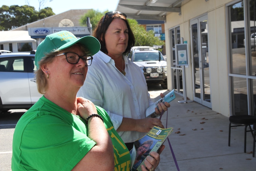 Two women standing in a car park holding election campaign flyers. 