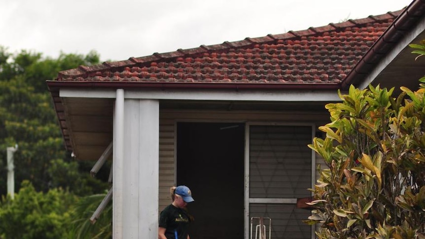 Children clear mud from the front steps of their flooded home in Fairfield, Brisbane