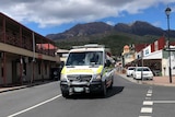 An ambulance in the main street of Queenstown, in Tasmania's west, with Mount Lyell in the background