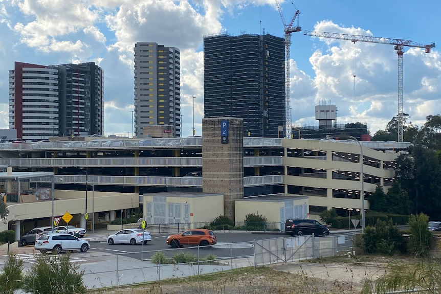 Three buildings in the distance behind a concrete ramp with cars