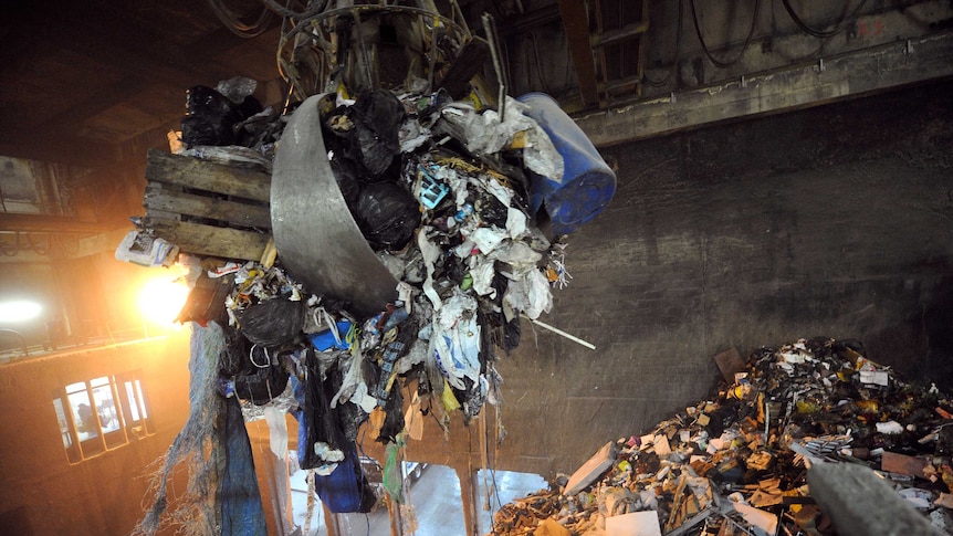 A claw scoops up garbage at an incinerator