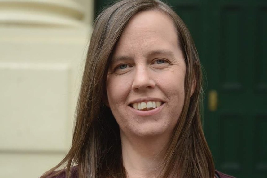 Woman with brown hair, wearing maroon top.