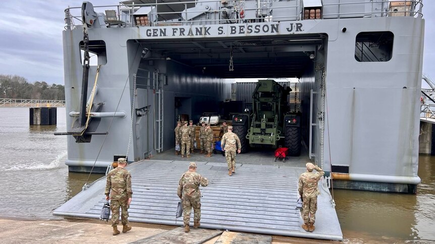 Ten US soldiers stand in uniform in front of the Frank S Besson military ship. 