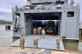Ten US soldiers stand in uniform in front of the Frank S Besson military ship. 