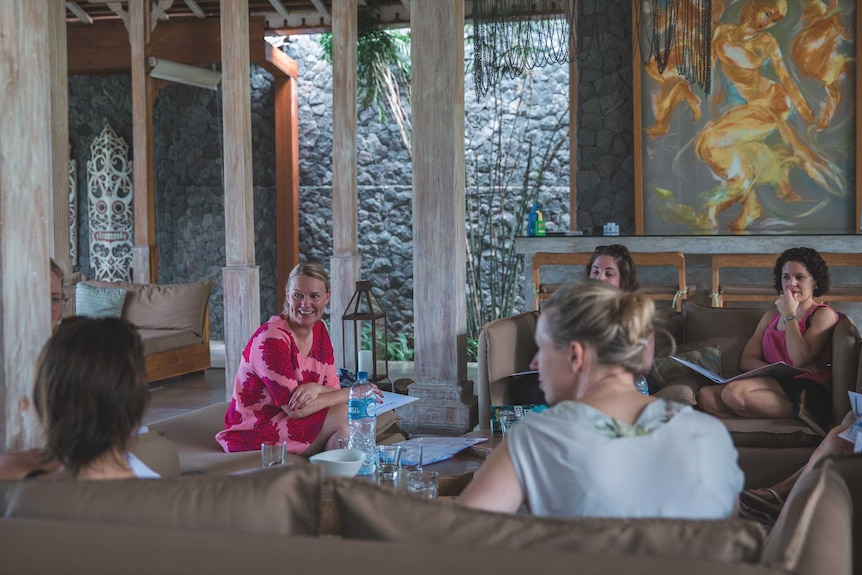 A group of women sit in a resort-like living room.