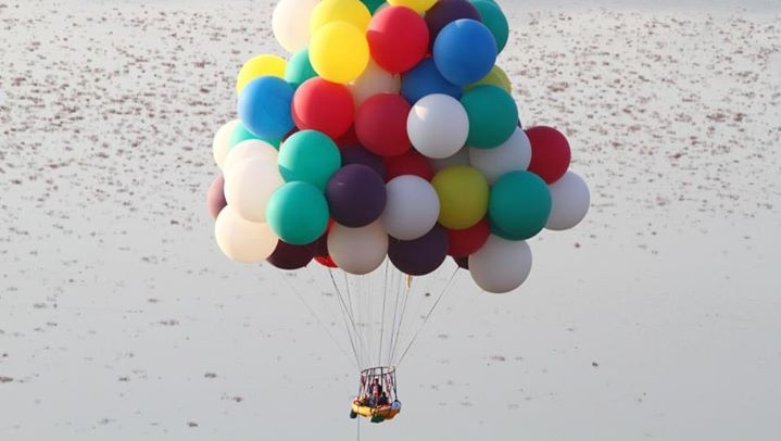 Jonathan Trappe in floats through the air in his boat suspended by helium balloons.