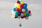 Jonathan Trappe in floats through the air in his boat suspended by helium balloons.