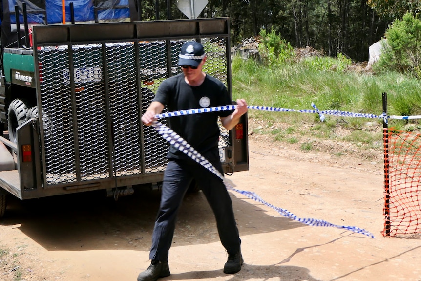 Police pulls blue and white tape across dirt track.