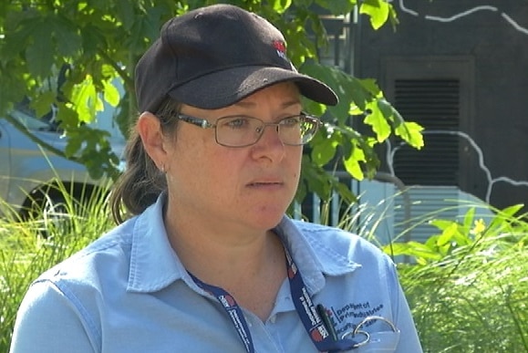 A NSW DPI officer with blue uniform and hat standing in front of a tree