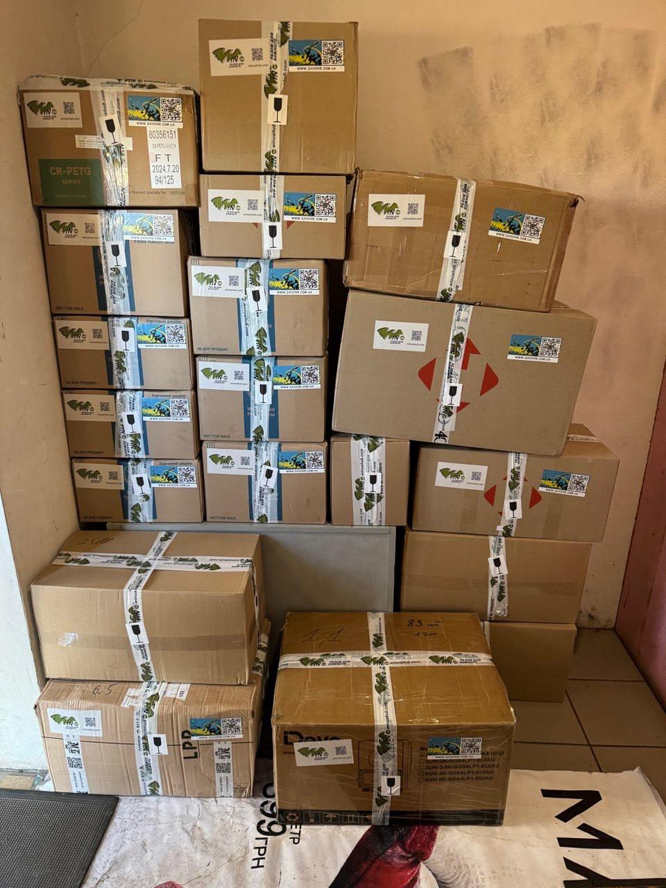 Boxes stacked high against a wall filled with 3D printed parts