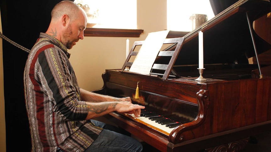 Harley Tait playing one of his four pianos in his Ringarooma home