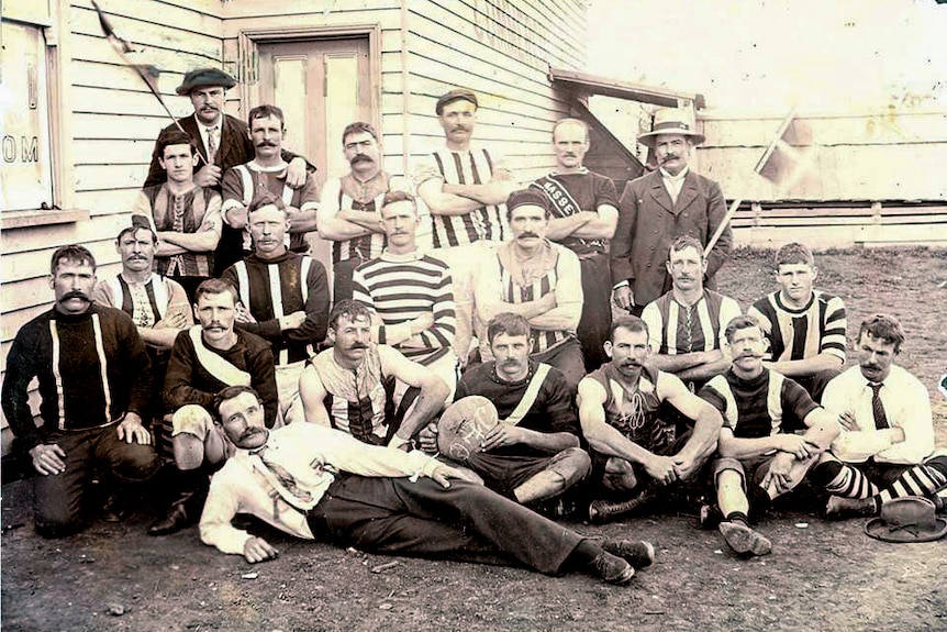 Black and white photo of men wearing old fashioned football uniforms