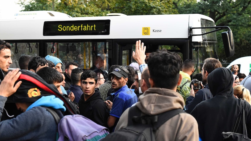 Refugees queue for bus in Berlin