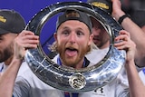 A Sydney FC A-League player puts his head through the circular hole in the championship trophy.