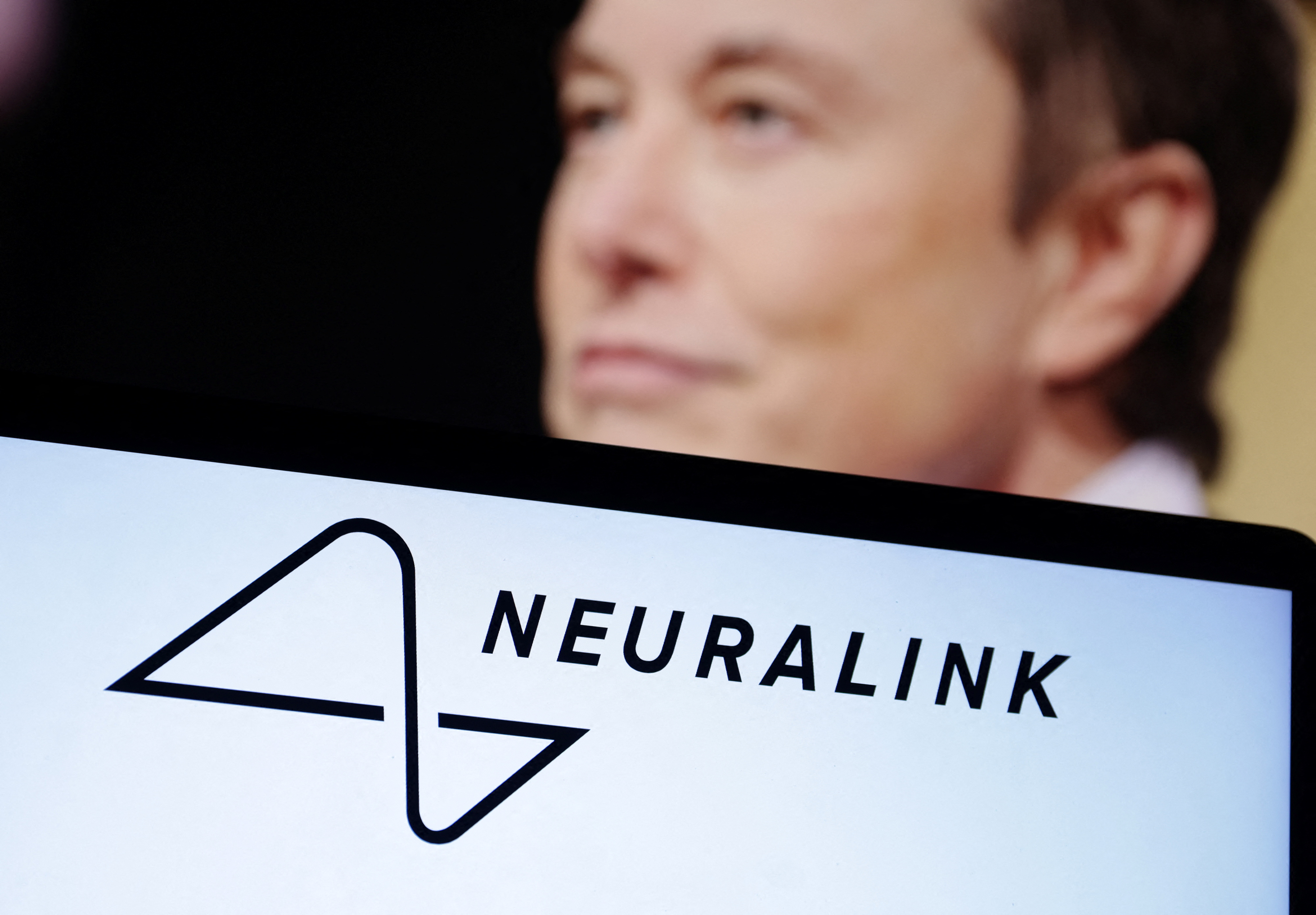 A man in the background of a Neuralink logo 