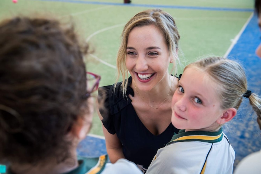 Hannah King (centre) a teaching school students is seen in the St Philip's Christian College playground with school students.