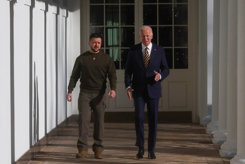 Joe Biden and Ukraine's President Volodymyr Zelenskyy walk down a corridor