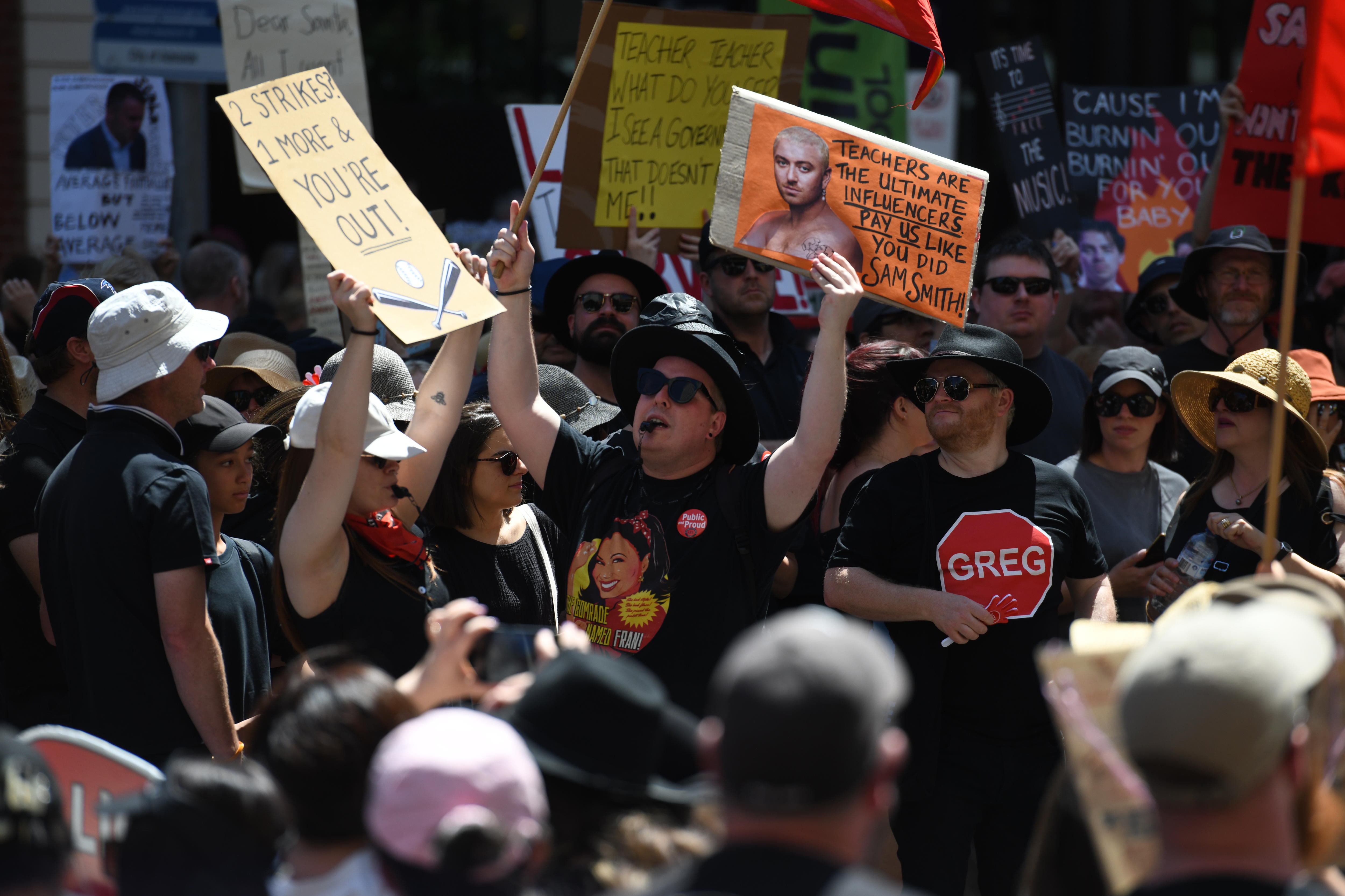 People hold up signs and chant at a protest.