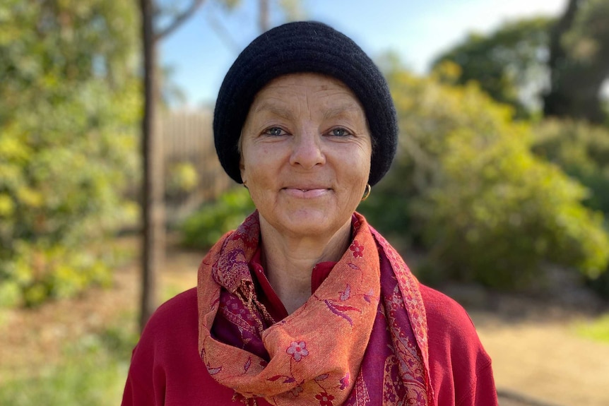 A portrait of a woman wearing a black beanie and red top and scarf.