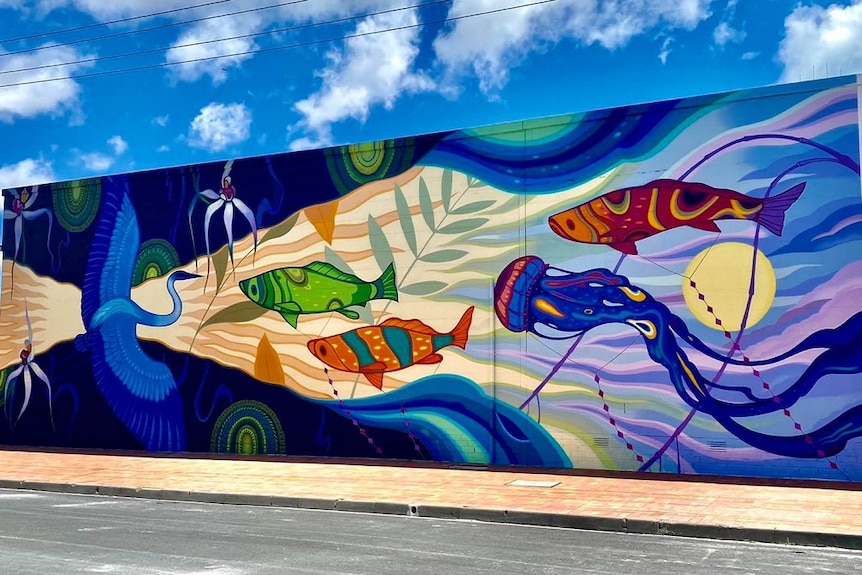 A colourful mural on an outside wall, with fish, jelly fish, a bird and orchids