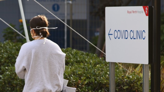 A woman stands outside a COVID-19 testing clinic with her back to the camera.