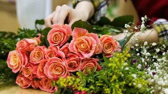 Roses being tied in a bunch by a florist.