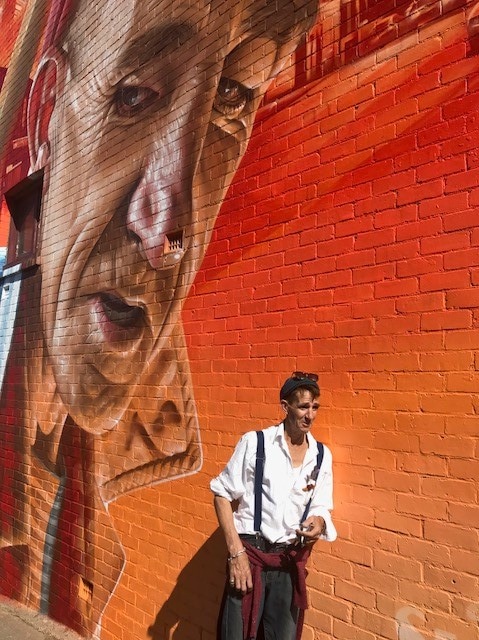 Cameron Williams with the SMUG mural showing his face in North Hobart