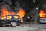 a man runs between cars that are ablaze in haiti
