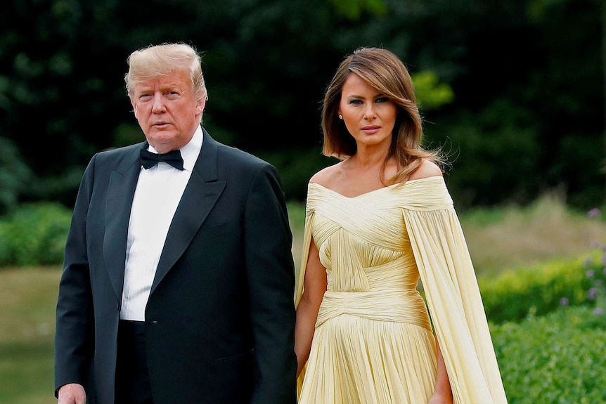 US President Donald Trump and the First Lady Melania Trump hold hands as they walk from the US ambassador's residence.