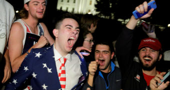 A group of young men in front of the White House struggle to contain their joy.