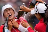 Amy Yang, in red shirt and white bucket hat, has champagne poured on her by other golfers after winning the PGA Championship.