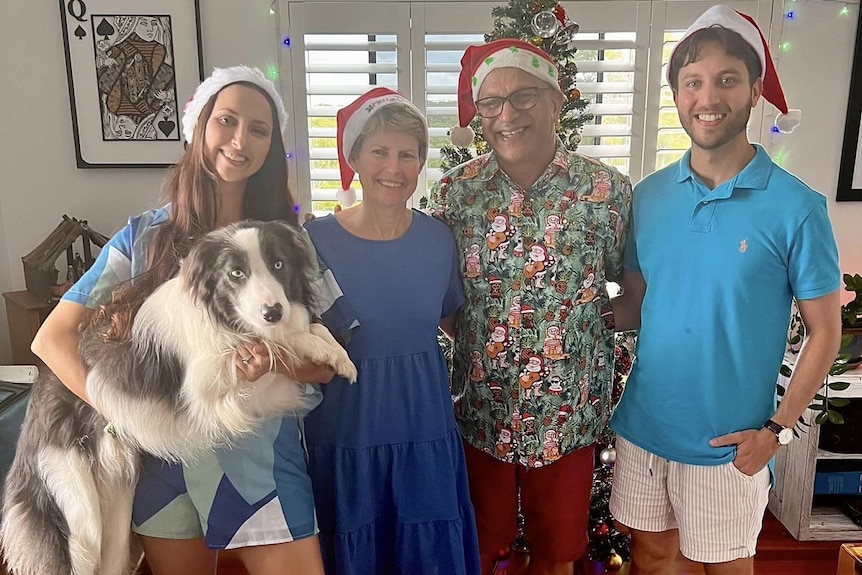 A smiling family in Christmas hats.