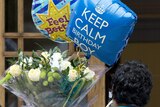A man arrives with flowers and balloons for Prince Philip at the London Clinic.